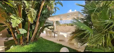 a patio with a table and chairs and palm trees at Villa Ruffino in Balestrate