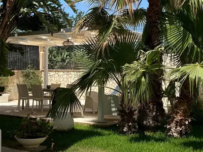 a patio with a table and chairs and palm trees at Villa Ruffino in Balestrate