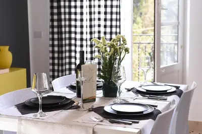 a table with plates and glasses and a bottle of wine at Chic Apartment Le Monde in Castellammare del Golfo