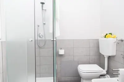 a bathroom with a toilet and a glass shower at Orlando Bayview in Balestrate