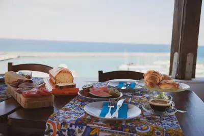 a table with bread and pastries on a table with the beach at Orlando Bayview in Balestrate