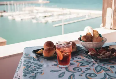 a table with a plate of food and a drink at Orlando Bayview in Balestrate