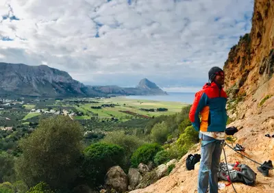 a man standing on the side of a mountain at Appartamento Il Pomodoro in San Vito lo Capo