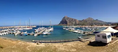 a group of boats docked in a marina with mountains at Appartamento Il Pomodoro in San Vito lo Capo