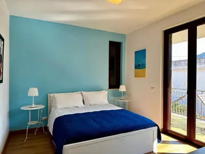 a blue bedroom with a bed and a balcony at Garden House Alla Torre in Isola delle Femmine