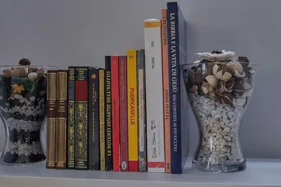 two vases sitting on a shelf with books at Palermo al Centro - Appartamento Vittorio in Palermo