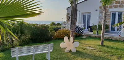 a white bench in the grass next to a house at Maresol in Trappeto