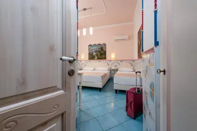 a room with two beds and a red suitcase at Albert Rooms & Breakfast in San Vito lo Capo