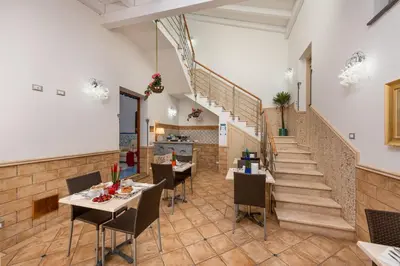 a restaurant with tables and chairs and a staircase at Albert Rooms & Breakfast in San Vito lo Capo