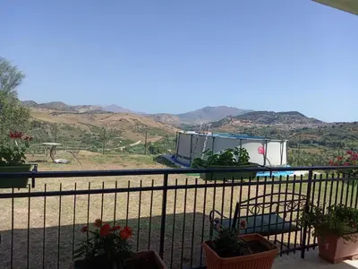 a balcony with a view of a pool and mountains at Villetta San Giovanni in Calatafimi
