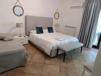 a bedroom with two beds with blue pillows and a chair at B & B Villa Flora in Mondello