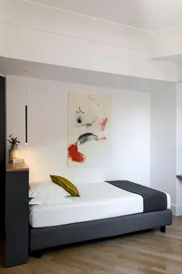 a bed in a bedroom with a white wall at Hotel Plaza Opéra in Palermo