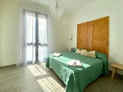 a bedroom with a green bed and a chandelier at Via Siracusa 5 in Castellammare del Golfo