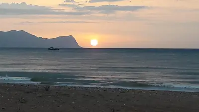 a sunset over the ocean with a boat in the water at Casa Vacanze TAMARA in Balestrate