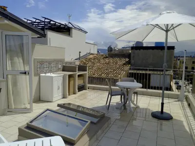 a patio with a table and an umbrella on a roof at Casa Vacanze TAMARA in Balestrate