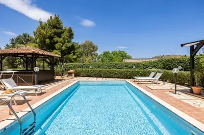 a swimming pool with two chairs and a gazebo at Villa Cocos in Casteldaccia