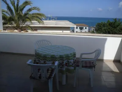 a table and two chairs on a balcony with the ocean at Vicino al mare e lontano dai rumori in Alcamo Marina