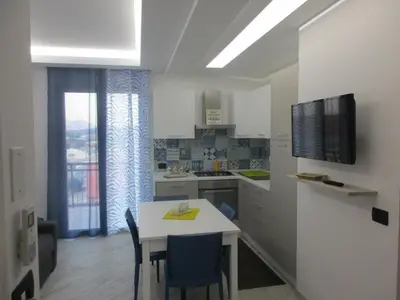 a kitchen with a white table and chairs and a television at Le Dimore di Enea in Castellammare del Golfo