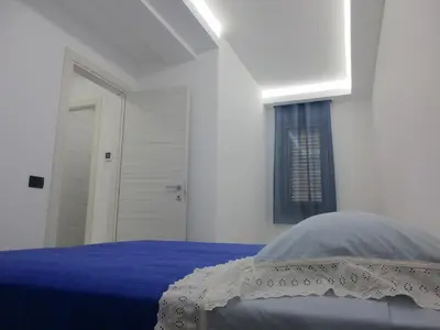 a bedroom with a bed with a blue bedspread and a window at Le Dimore di Enea in Castellammare del Golfo