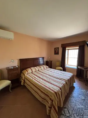 a bedroom with a bed and a chair and a window at Palazzo Q-tò in Monreale