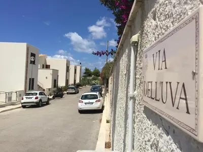 a street with cars parked on the side of a building at Un mare di Blu - Casa Cobalto in Macari