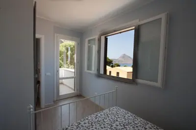 a room with two windows and a bed with a view at Un mare di Blu - Casa Cobalto in Macari