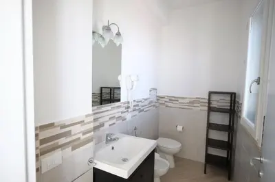 a white bathroom with a toilet and a sink at Un mare di Blu - Casa Cobalto in Macari