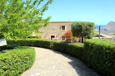a hedge path leading to a house with a building at Casale Maddalena in Carini