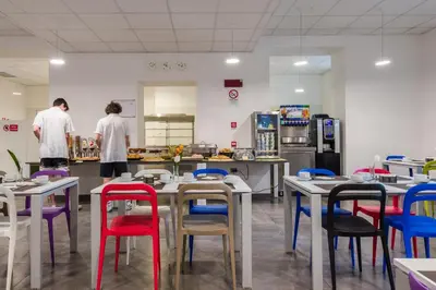 two people in a kitchen with tables and chairs at Camplus Palermo Normanni - in Palermo