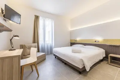 a hotel room with a bed and a desk and a chair at Camplus Palermo Normanni - in Palermo