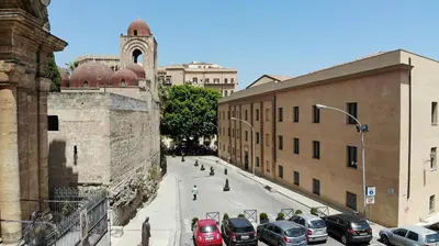 a street with cars parked in a city with a clock tower at Camplus Palermo Normanni - in Palermo