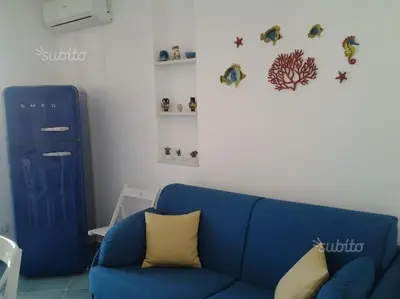 a blue couch in a living room with fish on the wall at Residenza del Mare & SPA in San Vito lo Capo