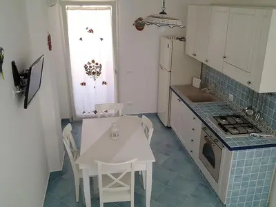 a kitchen with a table and a white table and chairs at Residenza del Mare & SPA in San Vito lo Capo