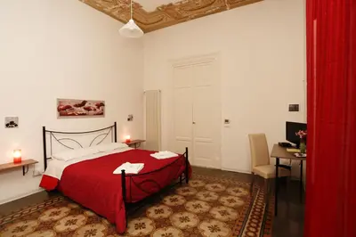 a bedroom with a red bed and a table and a desk at Rest and Go in Palermo