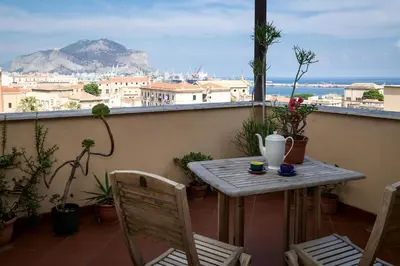 a table and chairs on a balcony with a view of the city at Panoramica Blu in Palermo