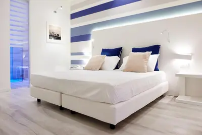 a bedroom with a white bed with blue and white stripes at Marina di Petrolo Hotel & SPA in Castellammare del Golfo