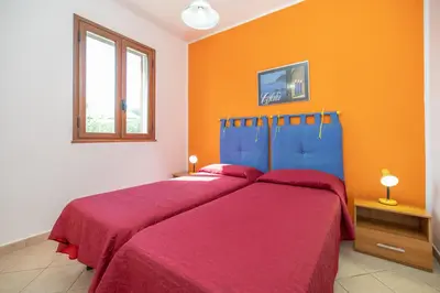 two beds in a bedroom with an orange wall at Arvilla's Houses in Campofelice di Roccella