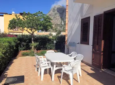 a white table and chairs with a mountain in the background at Appartamento con Giardino - WIFI in San Vito lo Capo