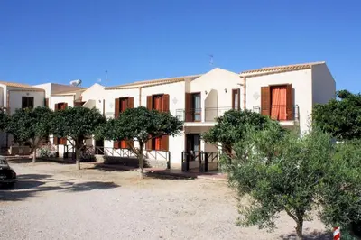 a large white building with trees in front of it at Appartamento con Giardino - WIFI in San Vito lo Capo