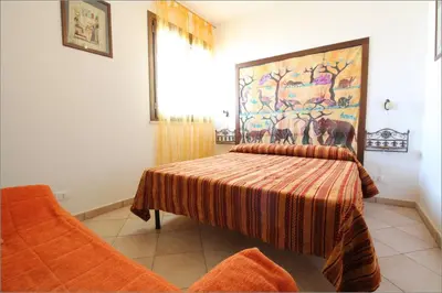 a bedroom with a bed with a painting on the wall at Senia in San Vito lo Capo