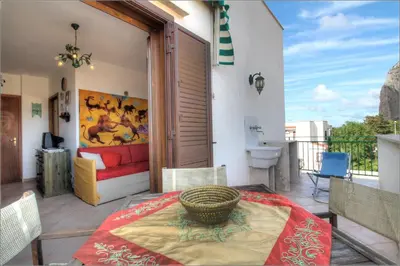 a patio with a table and a couch on a balcony at Senia in San Vito lo Capo