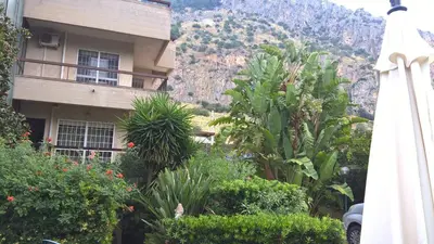 a building with a bunch of plants and a mountain at Villa Ania in Mondello