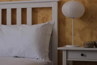 a bed with a white pillow and a lamp on a night stand at B&B Gallidoro in Palermo