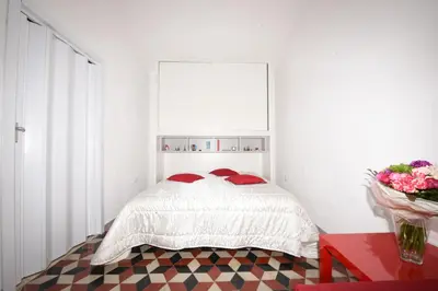 a white bedroom with a bed with red pillows at Terrazza in Palazzo Taormina in Castellammare del Golfo