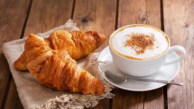 a cup of coffee and croissants on a table at 