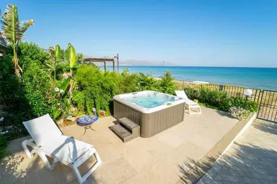 a hot tub sitting on a patio next to the ocean at Dune Home alloggi sul mare in Alcamo Marina