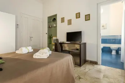 a bedroom with a bed and a desk and a television at MassimoCentro Rooms in Palermo