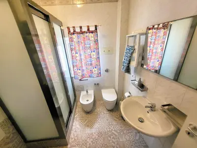 a bathroom with a sink and a toilet and a mirror at Seafront House Gabbiano Azzurro in Santa Flavia
