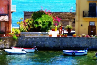a group of boats in the water next to buildings at Seafront House Gabbiano Azzurro in Santa Flavia