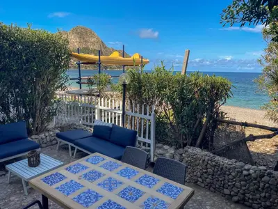 a patio with a table and chairs and the ocean at Dimore di mare - Beachfront Apartments in Santa Flavia
